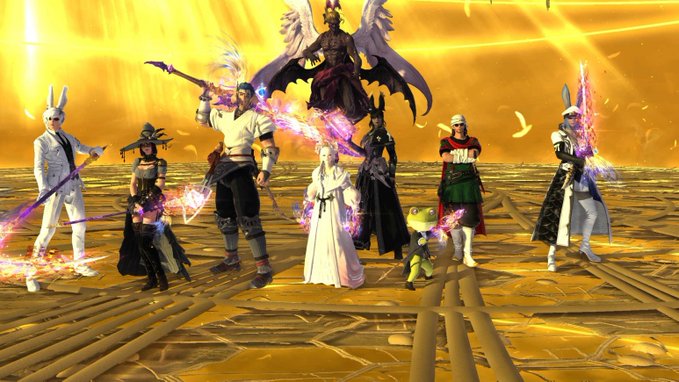 A group of various characters from Final Fantasy XIV, including the Warrior of Light and a large winged Bahamut-like entity, standing together on a glowing golden patterned floor.