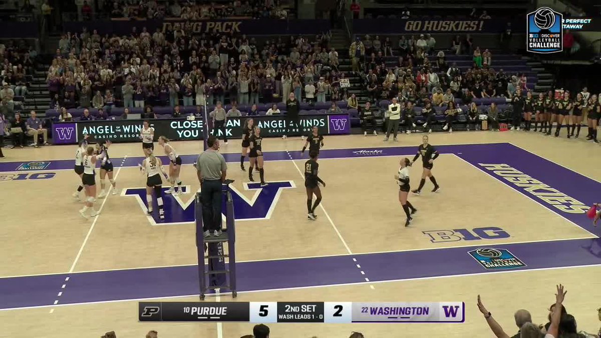 A college volleyball match between #10 Purdue and #22 Washington shows the score at 5-2 in the 2nd set, with Washington leading 1-0, played on a court featuring a large purple 'W' logo with 'GO HUSKIES!' visible in the stands.