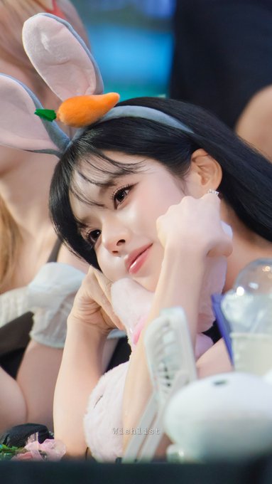 A young woman with bunny ears headband poses with her hand near her face, with 'Wishlist' watermark visible.