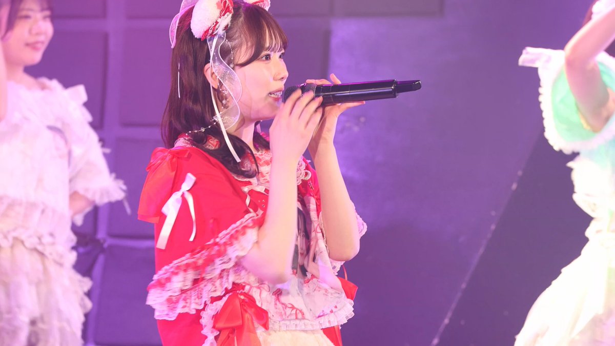 A young performer in a frilly red and white costume with a decorative headpiece sings into a black microphone on stage, bathed in purple lighting. The image captures the solo concert "Kekki Shūkai" by the idol group Falench., featuring member Hīragi Rika.