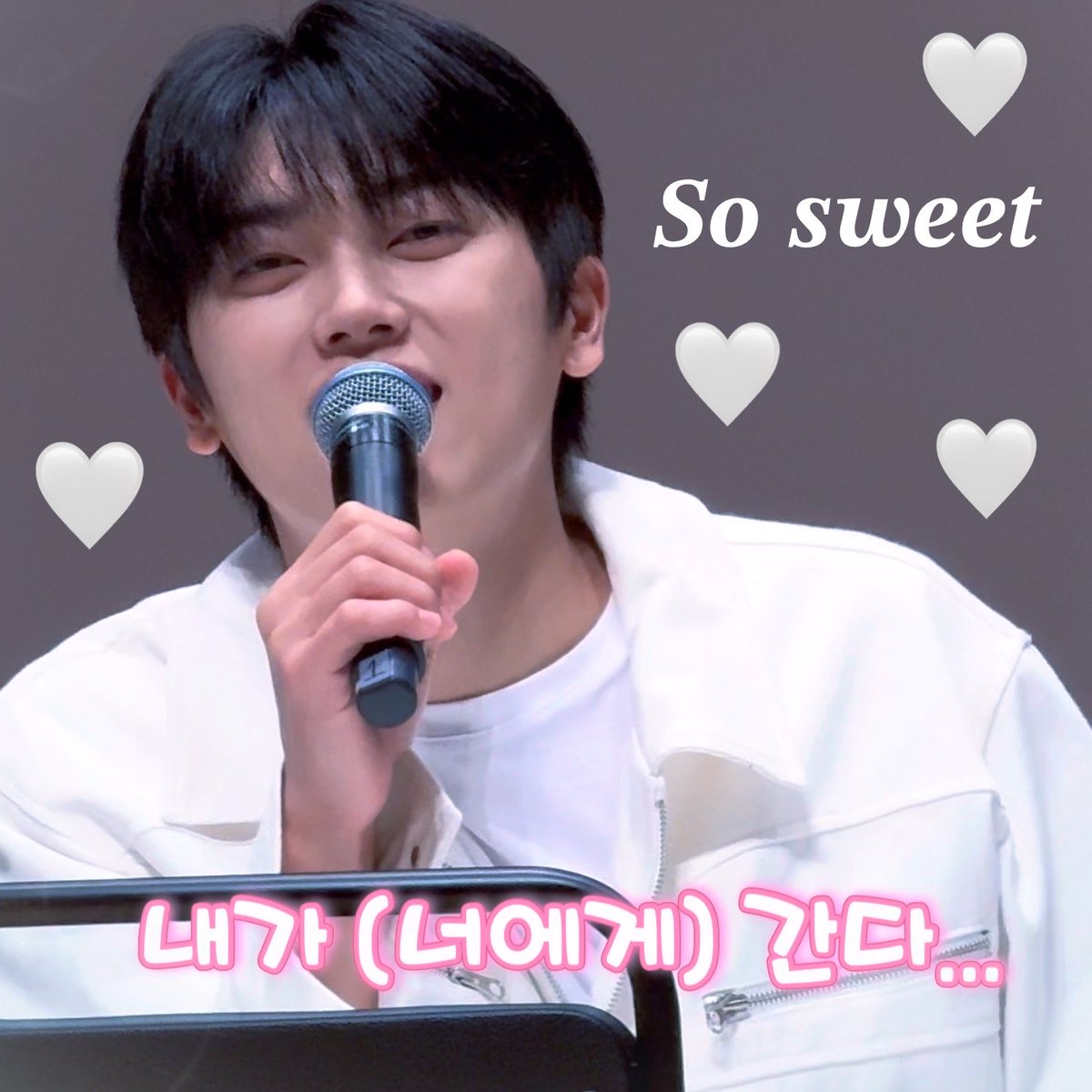 A fan-edited image of a young man in a white jacket holding a microphone with a gentle smile, decorated with white heart emojis and 'So sweet' text in pink Korean lettering.