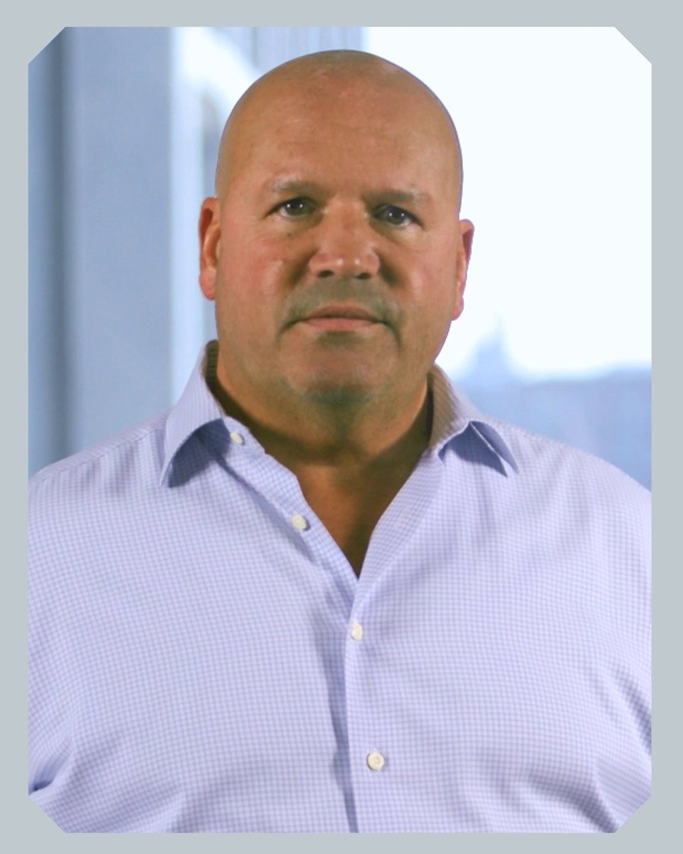 A bald man wearing a light purple checkered button-up shirt is pictured in what appears to be a professional headshot against a softly lit background. The image accompanies a post promoting CME Direct mobile alerts, which deliver real-time trading notifications to users on the go.