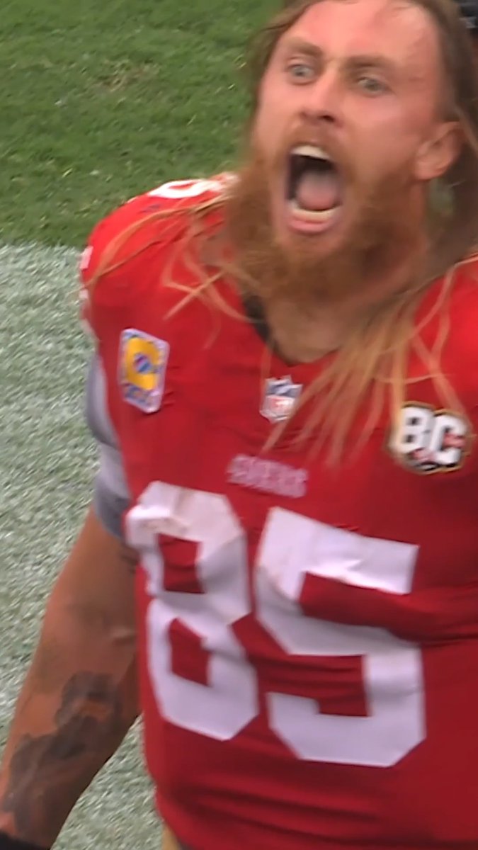 A 49ers football player with a long red beard yelling intensely while wearing a red jersey with number 89.