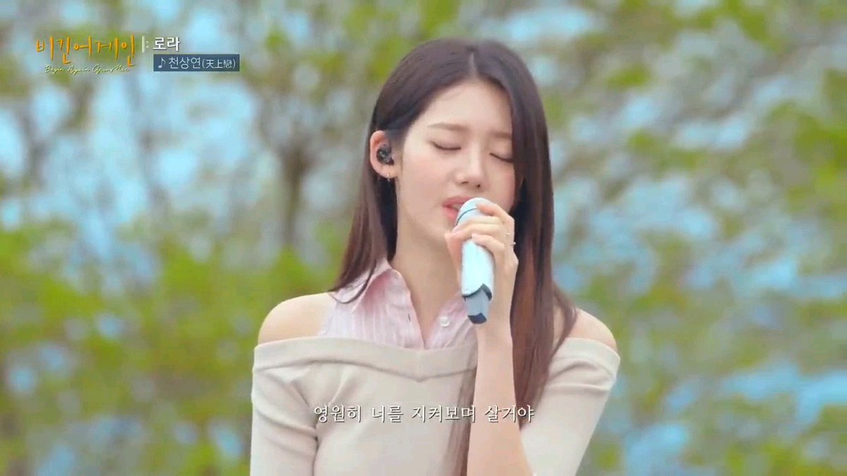 A still from a Korean music program showing a female singer performing with her eyes closed; on-screen text includes '비긴어게인', '윤라', '전상현(天上班)', and lyrics '영원히 너를 지켜보며 살거야'.