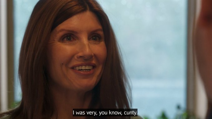 A close-up of a smiling woman with brown hair during an interview, with the subtitle 'I was very, you know, cunty.' displayed at the bottom.