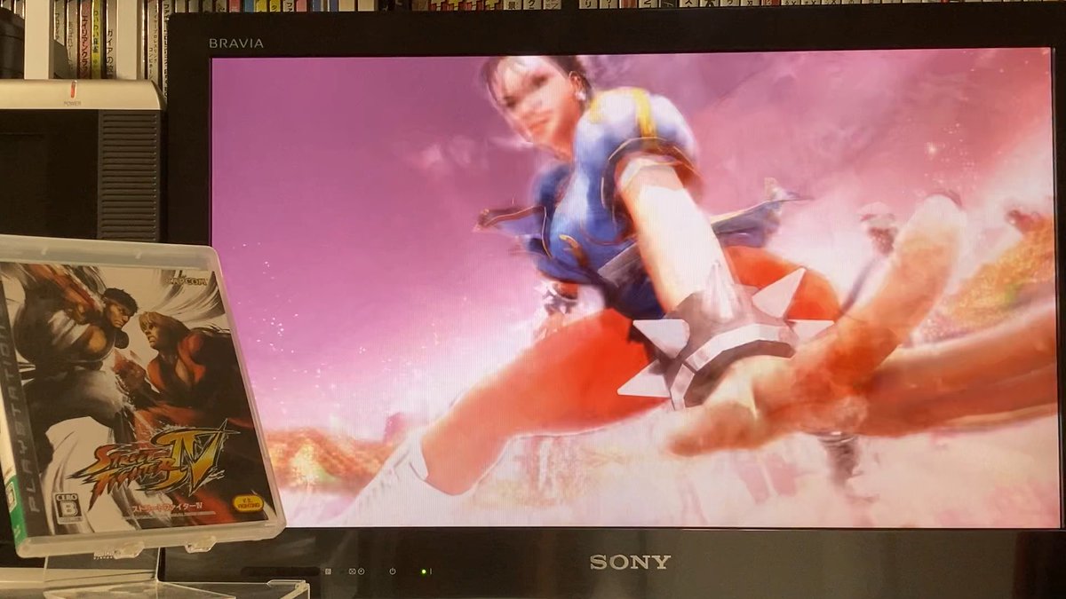 A Sony BRAVIA television displaying the Street Fighter IV video game title screen featuring Chun-Li, with the PlayStation 3 game case for 'Street Fighter IV' visible in the foreground next to a PS3 console.