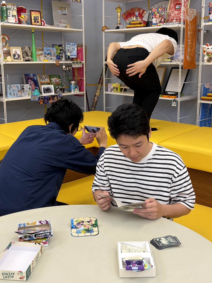 omocoroch's tweet photo. ボードゲームの説明書を読み込む副社長と、ケツの写真を撮らせる社員
#オモコロチャンネルのオフショット https://t.co/GdUWn3HxpC