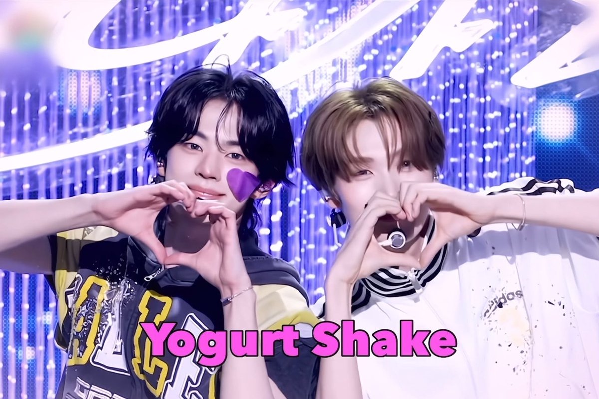 Two young performers on a stage make heart shapes with their hands while looking at the camera, with "Yogurt Shake" displayed in pink text at the bottom and "#빵또즈" (Bbangtoz) as the associated hashtag.