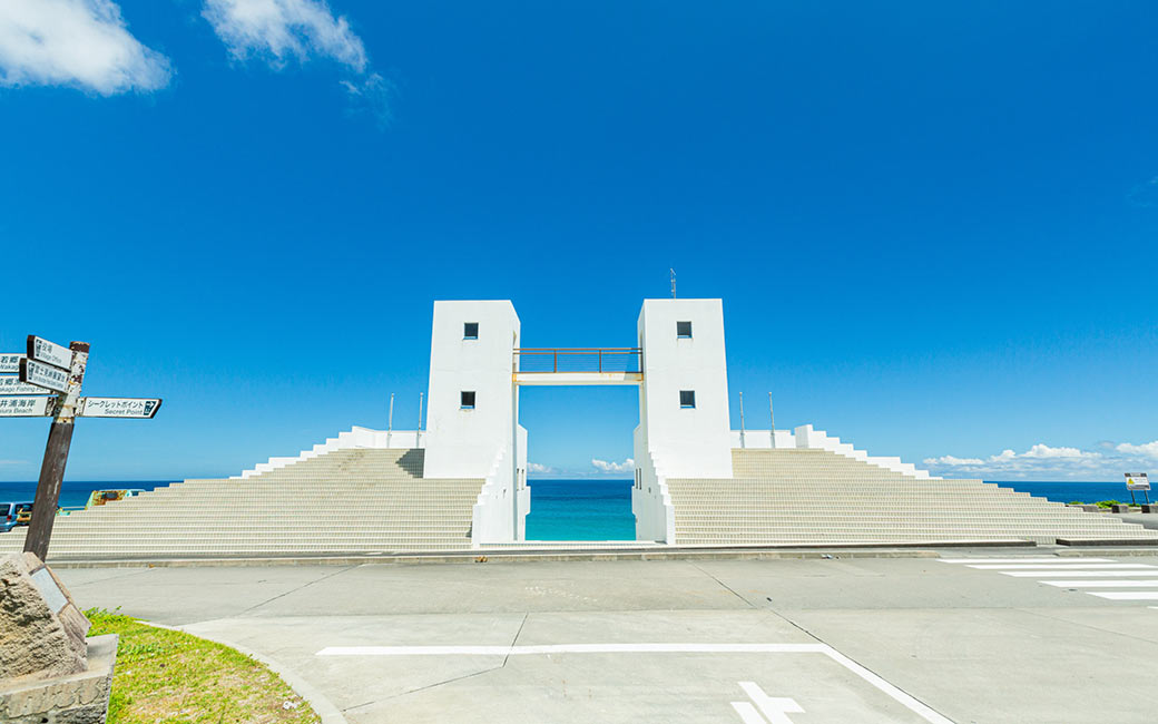 chill_tabi_2026's tweet photo. 🏝️【#新島 チル旅スポット紹介 Vol.1】
羽伏浦メインゲート（羽伏浦海岸）

新島を訪れたら絶対に外せない超定番スポット！
「羽伏浦海岸」にある、真っ白なメインゲートです。

ゲートのフレーム越しに見えるエメラルドグリーンの海と青空は、まさに絵画のような美しさ🎨
青い空と白いゲートのコントラストが抜群で、写真映えも間違いなしのチルスポットです📸

約7kmにわたって美しい白砂が続く羽伏浦海岸で、波の音を聴きながらのんびり散歩するのもおすすめ。

💡今後も新島・式根島の魅力を伝える観光スポットやグルメシリーズをお届けしていきます！お楽しみに！

#羽伏浦海岸 #チル旅 #プレゼント