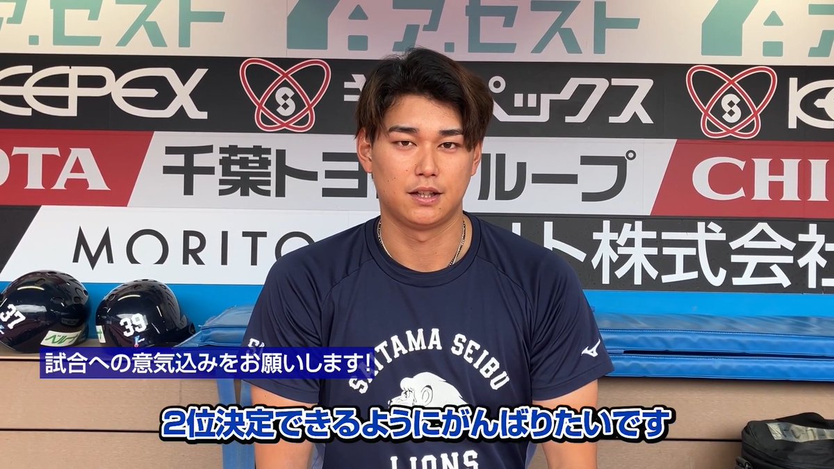 A baseball player from the Saitama Seibu Lions, wearing jersey number 39, stands in front of a sponsor-covered backdrop featuring logos including EPEX, Toyota, and Morito, with Japanese subtitles reading "I want to work hard to clinch second place" — reflecting his determined message to fans ahead of a game in Chiba.