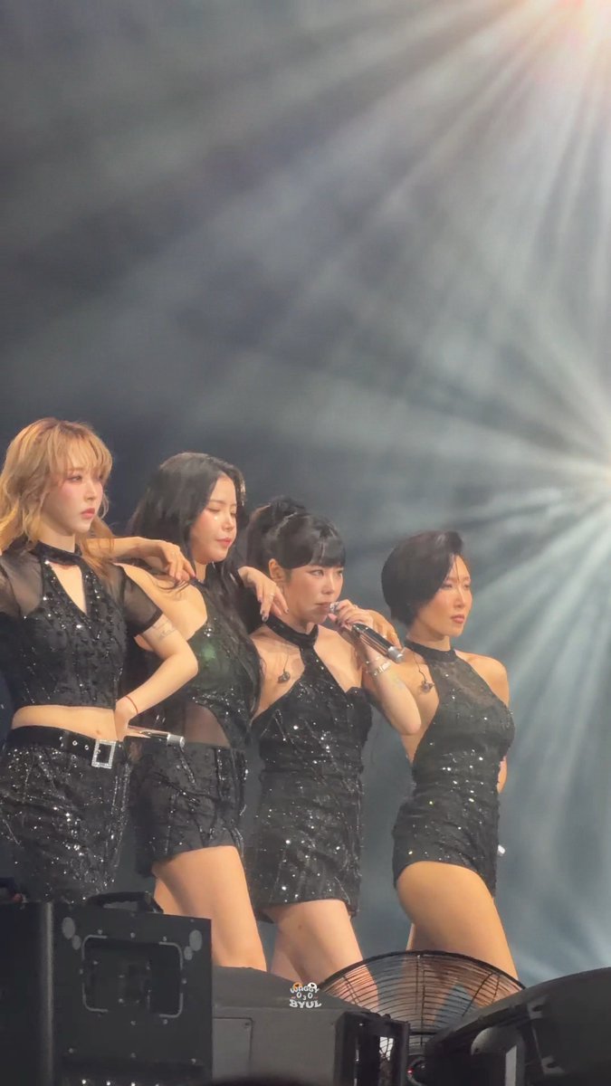 Four women perform on stage in sparkling black outfits, with a microphone visible and a watermark reading "GIRLS GONE SYUL" in the corner.