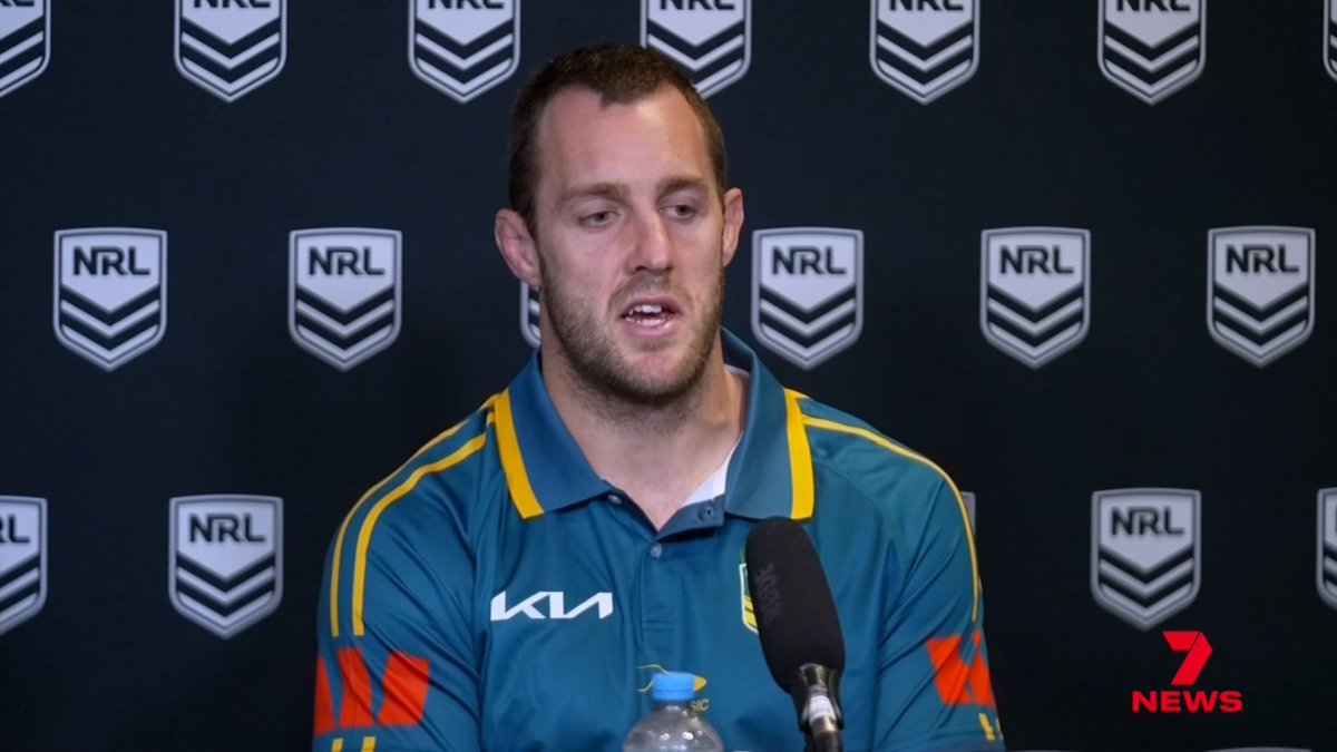 A man in a teal and gold KIA-sponsored polo shirt speaks into a microphone at a press conference, with an NRL logo backdrop and a 7 News watermark visible, likely addressing his inclusion in Australia's World Cup squad following a grand final appearance.
