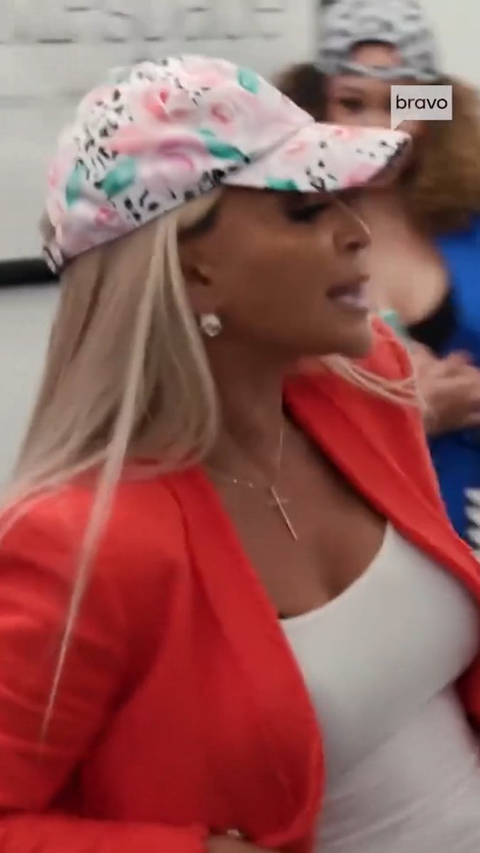 A blonde woman wearing a floral cap and a vibrant red blazer over a white top is captured mid-conversation, with a "bravo" watermark visible in the corner. The image, taken from The Real Housewives of Potomac, ties to the post promoting Season 11's premiere on October 11th.