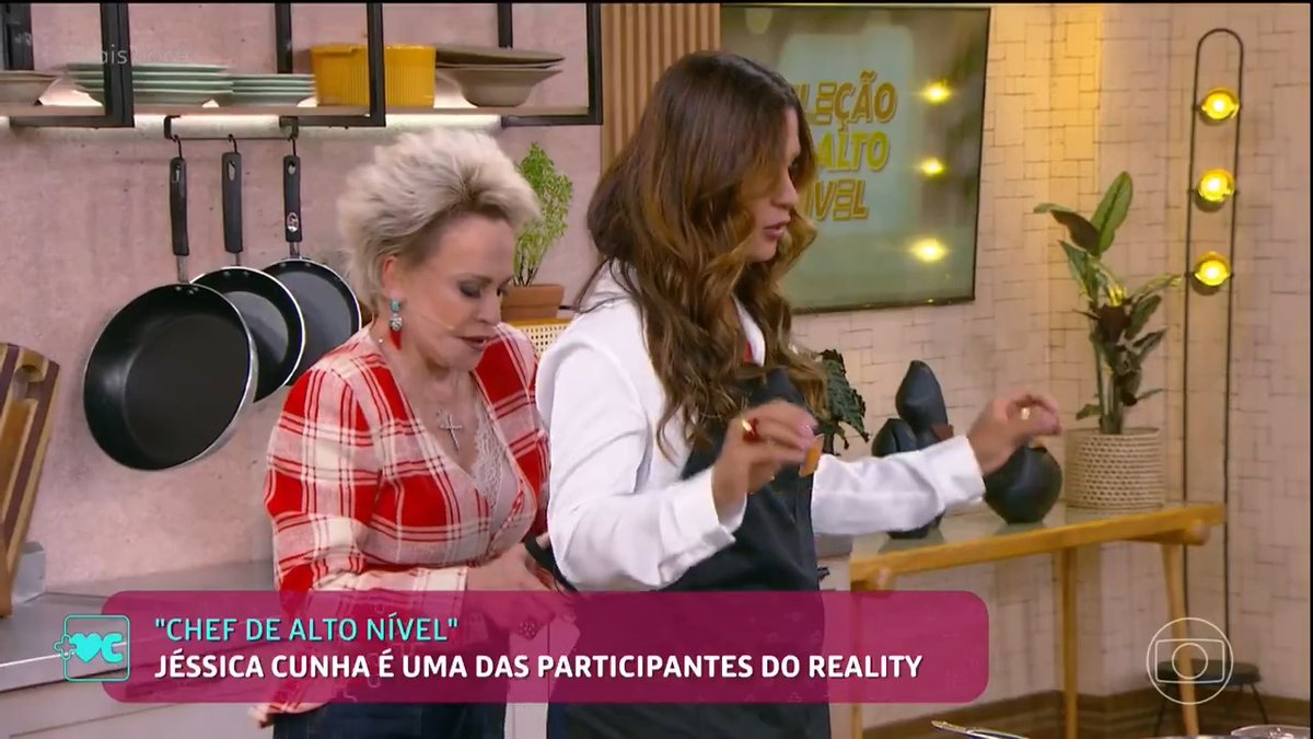 TV cooking show scene with two women in a kitchen; on-screen Portuguese text reads "CHEF DE ALTO NÍVEL" and "JÉSSICA CUNHA É UMA DAS PARTICIPANTES DO REALITY".