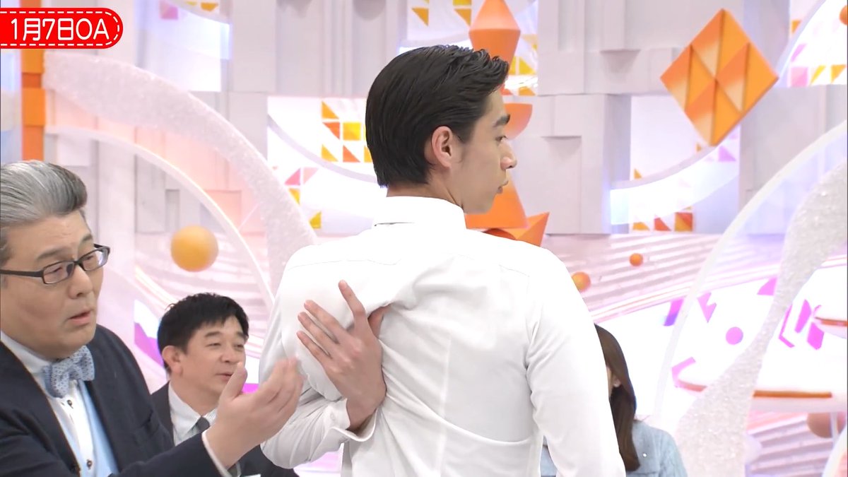 A screenshot from a Japanese television show, dated '1月7日OA', showing a man in a white shirt with his back to the camera, while an older man in a suit and glasses places a hand on his back.