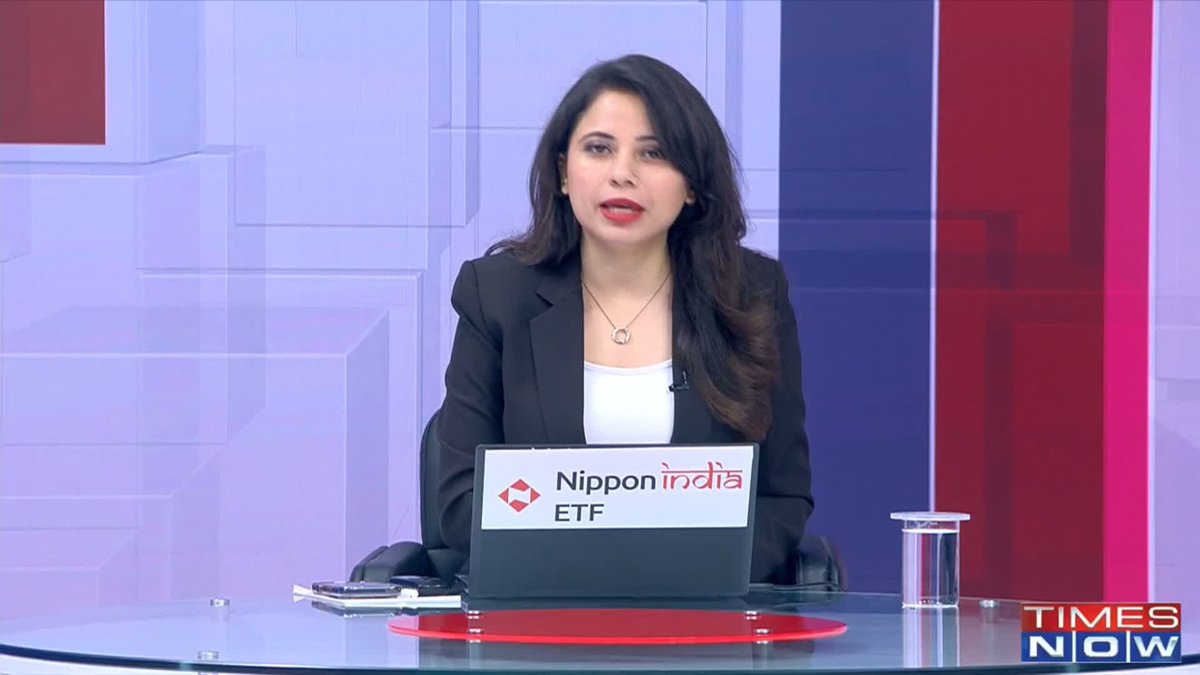 News anchor in a black blazer presenting from the Times Now studio, with a laptop displaying 'Nippon India ETF' on the desk in front of her.