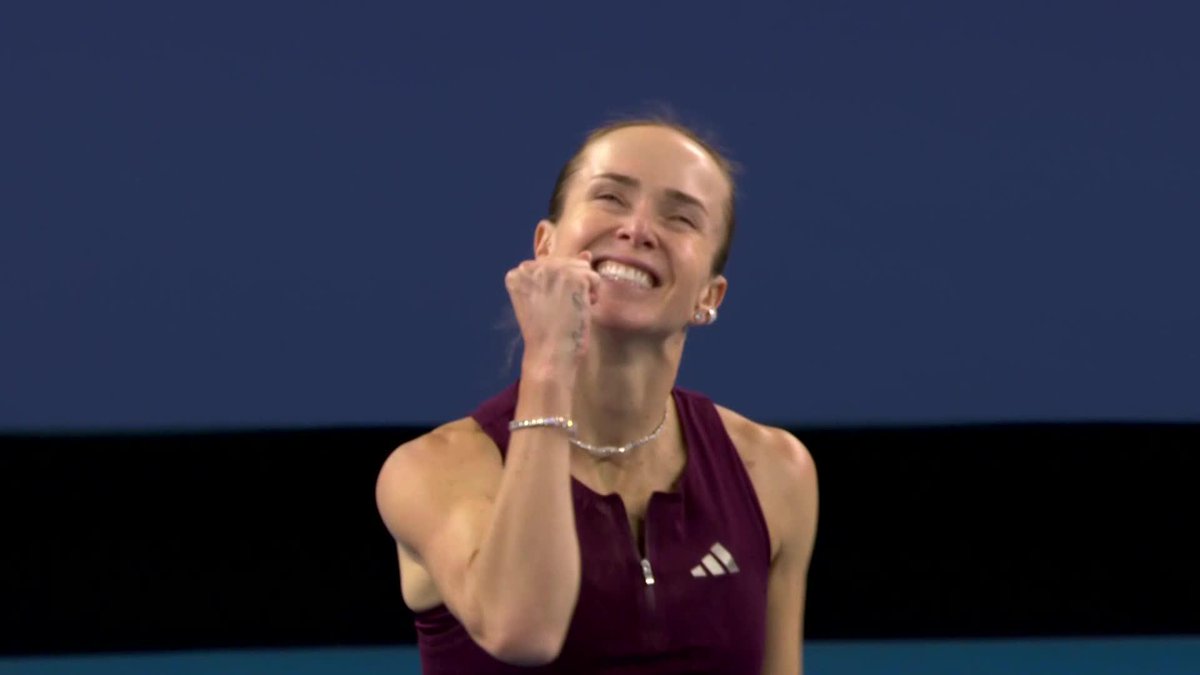 A female tennis player wearing a maroon Adidas top celebrates with a clenched fist and a wide smile, capturing the moment of her victory over Sakkari in Beijing as mentioned in the accompanying caption.