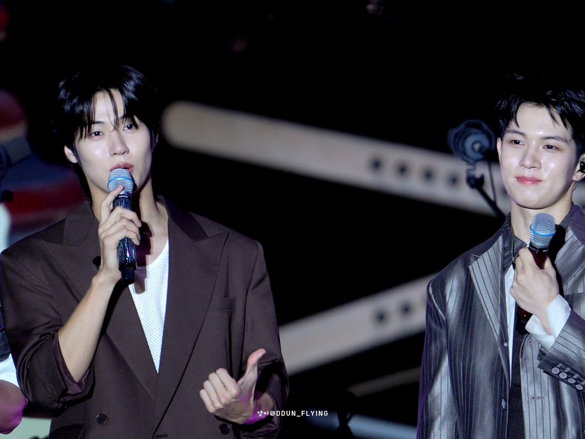 Two male performers holding microphones on stage, with a watermark reading '@DDUN_FLYING' visible.