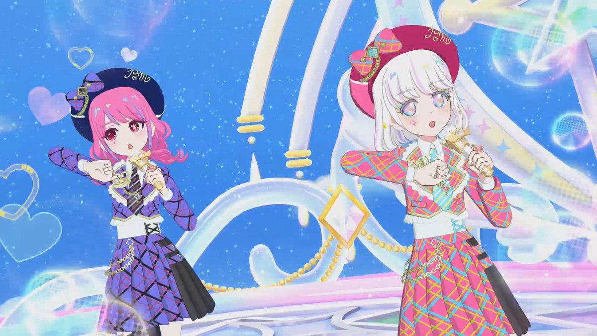 Two anime-style female characters singing into microphones on a sparkly stage; the pink-haired girl on the left wears a purple plaid outfit with a beret reading 'Jem', and the silver-haired girl on the right wears a pink plaid outfit with a matching beret.