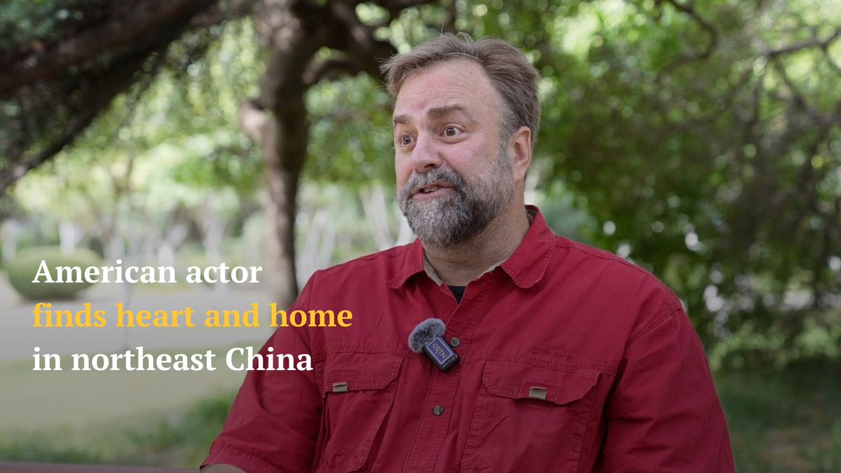 An American actor with a beard wears a red shirt and a CGTN microphone in front of trees, with text reading "American actor finds heart and home in northeast China."