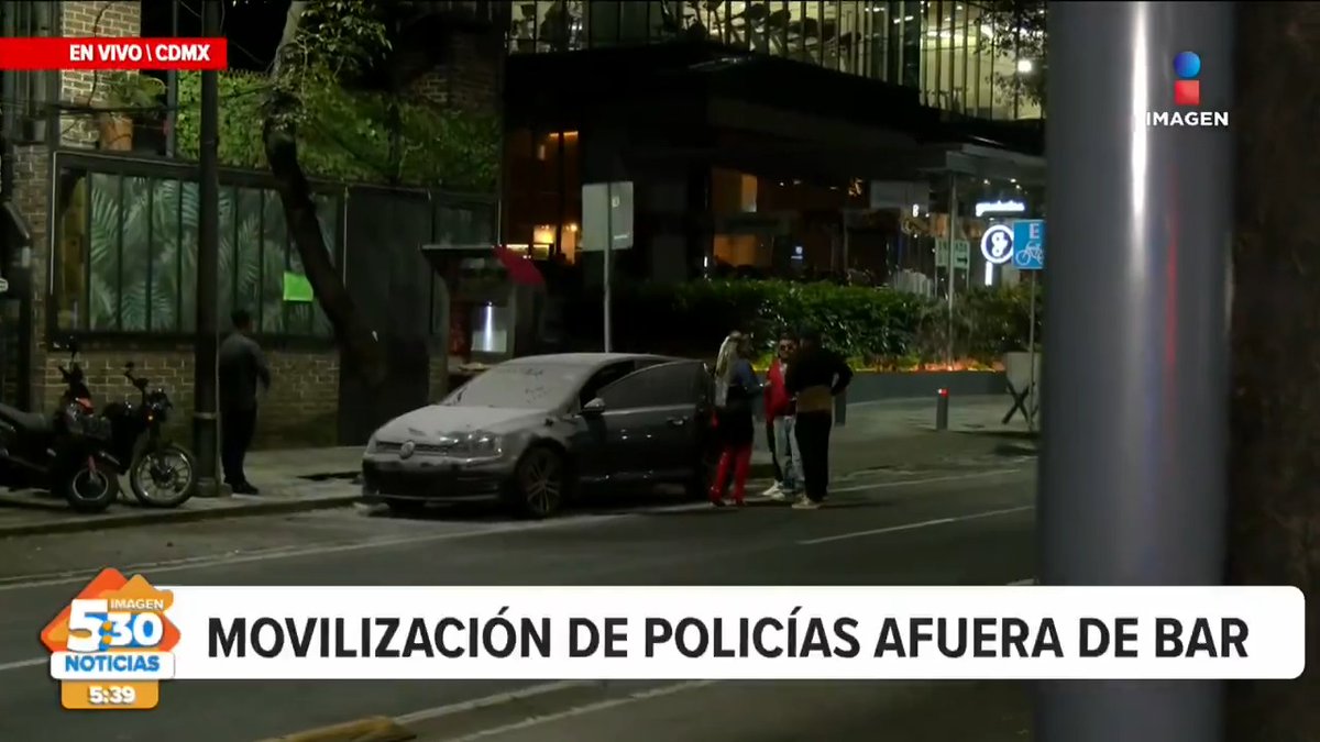 A news broadcast screenshot from 'Imagen Noticias' showing a nighttime street scene in CDMX with police and bystanders near a car, with the headline 'MOVILIZACIÓN DE POLICÍAS AFUERA DE BAR' and a timestamp of 5:39.