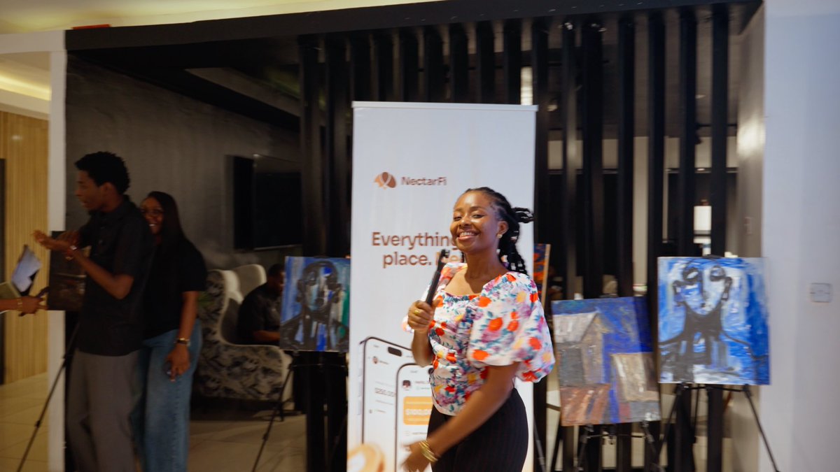 A smiling woman in a floral off-shoulder top speaks into a microphone beside a "NectarFi" banner reading "Everything in one place," surrounded by displayed artwork, capturing the lively energy of a missed event hinted at by the "FOMO wan wound me!" caption.