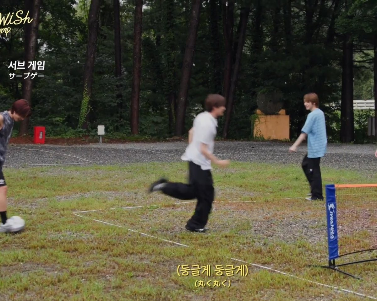 A screenshot from a Korean variety show showing young men playing foot volleyball outdoors in the rain, captioned '서브 게임' (Serve Game) and '동글게 동글게' (Round and round).