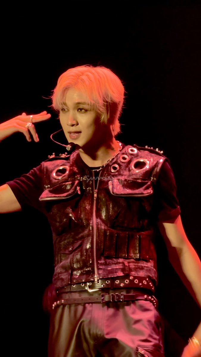 A performer with light pink hair poses on stage, wearing a black studded leather vest and pants, illuminated by dramatic red lighting. The watermark "balmwxe_" is visible on the image, capturing NCT 127 member Haechan during the group's 5th Neo City tour stop in Jakarta.