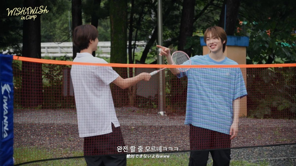 Two young men playing badminton on an outdoor court, with the 'WISH & WISH in Camp' logo in the top left and Korean/Japanese subtitles at the bottom.