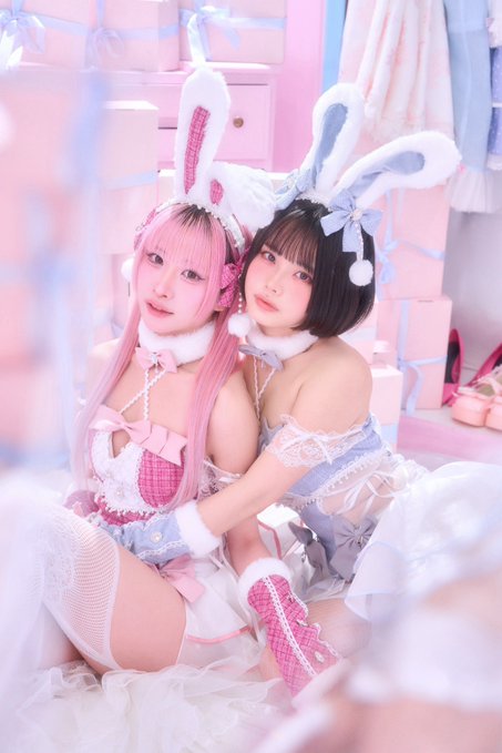 Two girls in pastel pink and blue bunny-themed maid costumes pose playfully together, evoking a sweet, flirtatious moment that aligns with the caption "I got caught♡." The soft, dreamy aesthetic and bunny ear headbands enhance the playful, mischievous tone of being caught in the act.