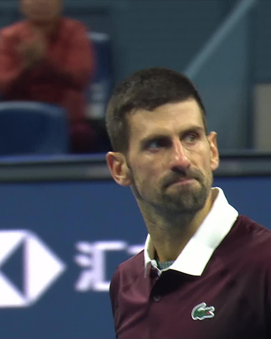 The image shows tennis player Novak Djokovic wearing a maroon Lacoste polo shirt, looking up with a focused expression on the court, with the US Open logo visible in the background. The caption relates to the post by highlighting Djokovic's intensity and athleticism, suggesting that his strong physical form at age 39 is evident in his concentrated, determined expression during the match.