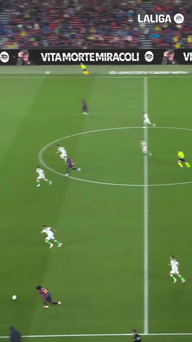 A screenshot from a LaLiga EA Sports soccer match broadcast shows players in white and blue-and-red striped uniforms on a green field, with an advertising board in the background reading 'VITA MORTE MIRACOLI' alongside a Spotify logo.
