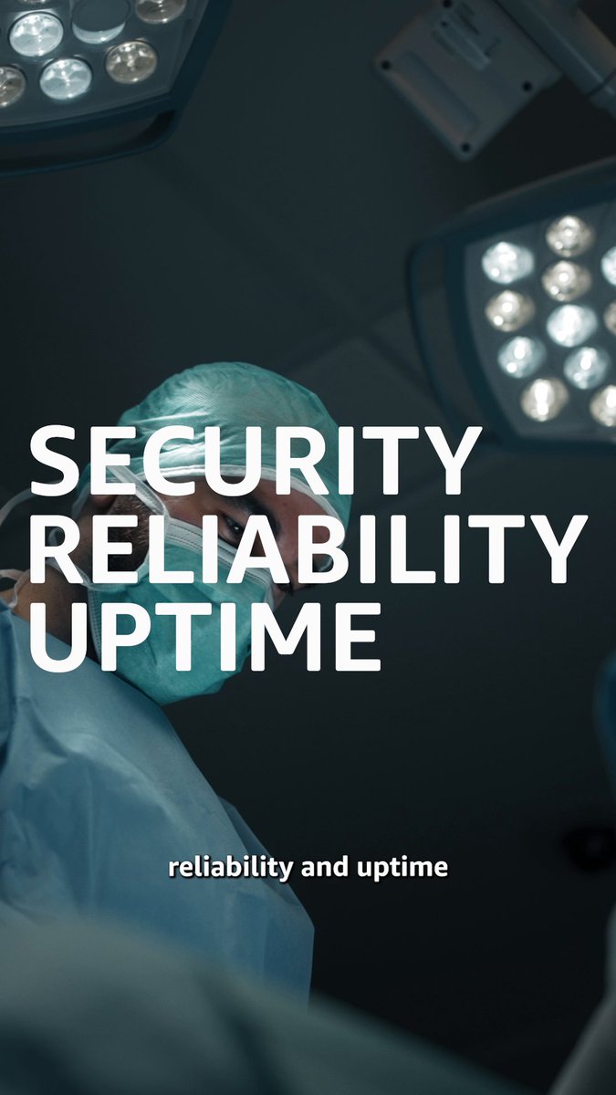 A low-angle shot of a surgeon in scrubs and mask looking down under bright operating room lights, overlaid with the bold white text "SECURITY RELIABILITY UPTIME" and smaller text reading "reliability and uptime".