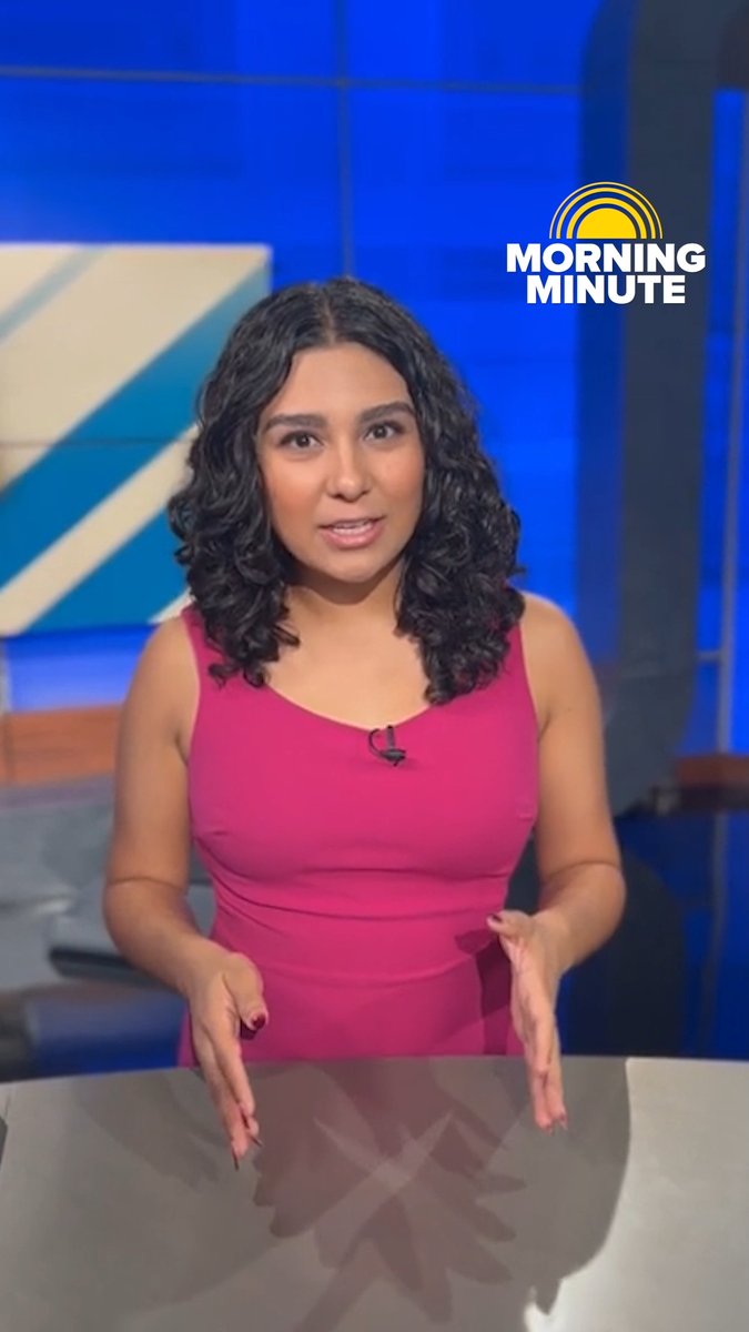 A news anchor in a pink sleeveless dress presenting on set with a 'MORNING MINUTE' logo in the upper right corner.