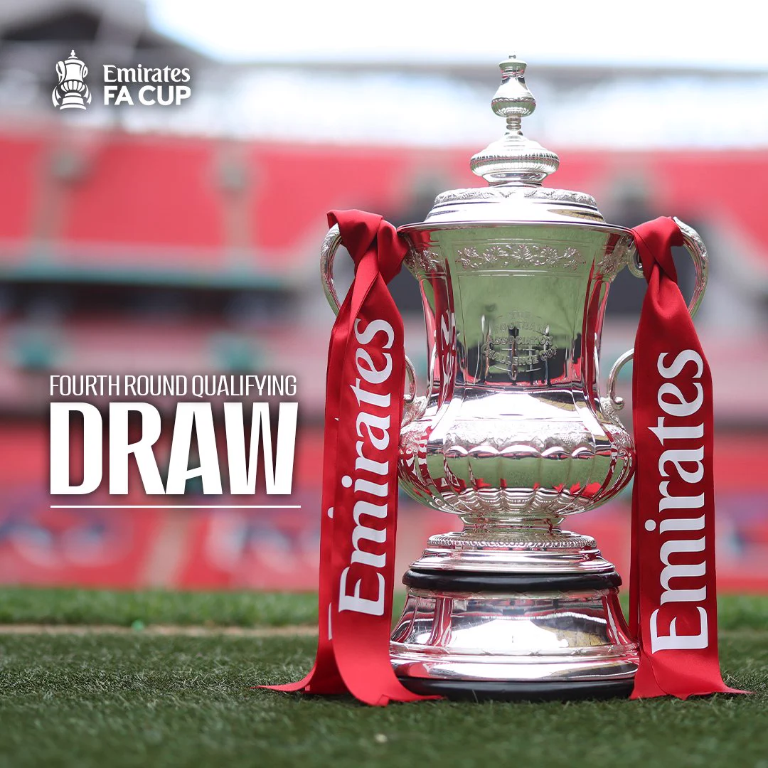 The Emirates FA Cup trophy stands on the pitch at Wembley Stadium, with red Emirates ribbons draped from both handles and blurred red stands behind. Text reads: Emirates FA Cup. Fourth round qualifying draw.