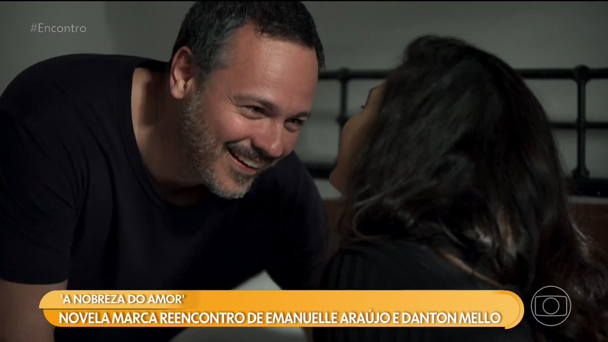 A scene from the Brazilian telenovela 'A Nobreza do Amor,' showing actors Danton Mello and Emanuelle Araújo sharing an intimate moment, with text reading '#Encontro' and a caption about their reconnection.