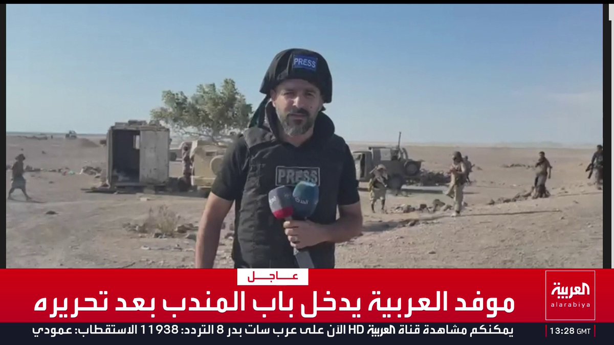 Al Arabiya correspondent reporting live from the front, wearing a PRESS helmet and vest in a desert warzone with soldiers and military vehicles behind him, while the Arabic news ticker reads "موفد العربية يدخل باب المندب بعد تحريره" (Al Arabiya correspondent enters Bab al-Mandab after its liberation), visually supporting the post's claim about Yemen being a critical frontline and "the gateway" to the Arabian Peninsula.