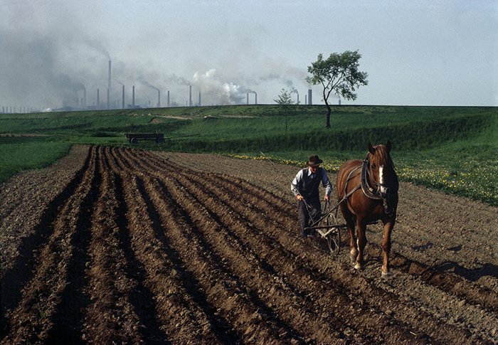 eastblocvisuals's tweet photo. Farmer ploughing a field near the Nowa Huta steel mills in Poland, 1981. https://t.co/FiQ1X4NSSt