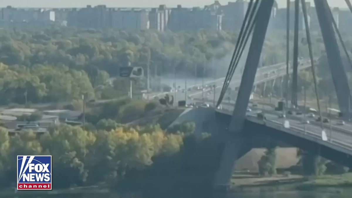 A Fox News Channel broadcast shows an aerial view of a bridge with military vehicles and smoke on a highway, with the network logo in the bottom left corner.