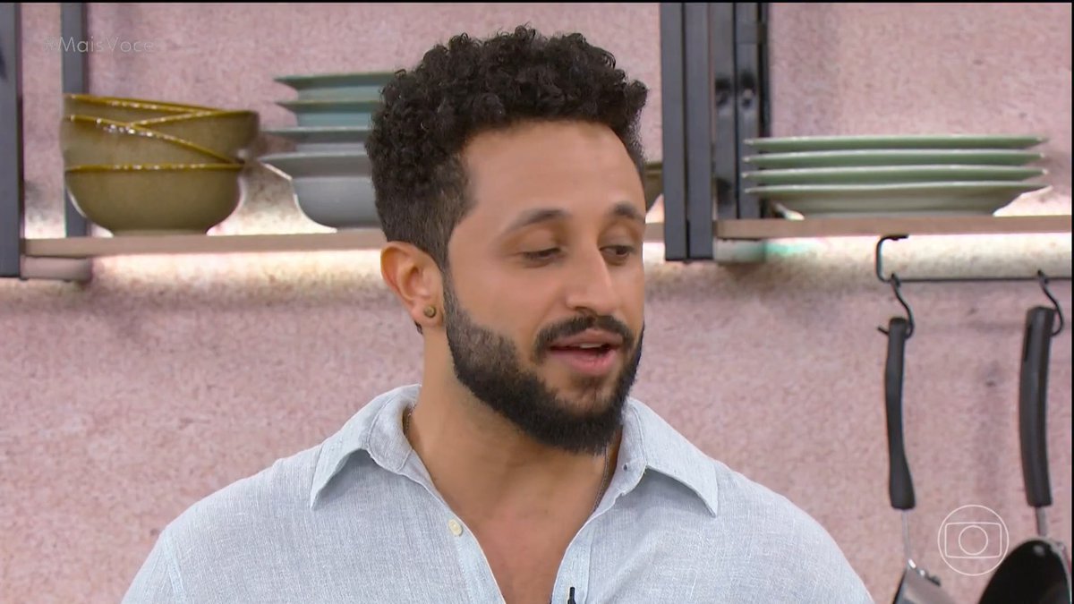 A bearded man with curly hair wearing a light blue shirt speaks in what appears to be a TV studio kitchen setting, with the '#MaisVoce' and Globo logo visible.