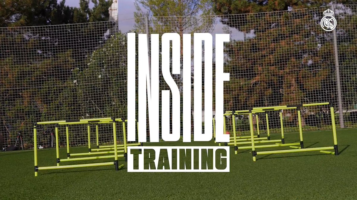 The image shows a Real Madrid training facility with neon yellow agility hurdles set up on the grass pitch, overlaid with bold white text reading "INSIDE TRAINING." The Real Madrid crest appears in the top right corner, tying the behind-the-scenes training setup to the club's first session of the week.
