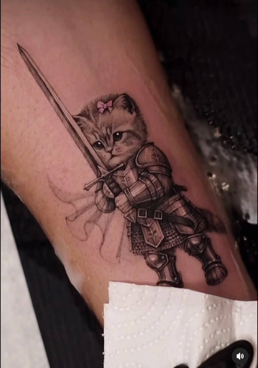 catlerone's tweet photo. Swordcat really went from a random AI meme to an actual tattoo.

People are literally putting this little armored cat on their skin now 😭

A few weeks ago it was just another viral AI character.

Now people are getting emotionally attached enough to make it permanent.

AI memes move fucking fast.