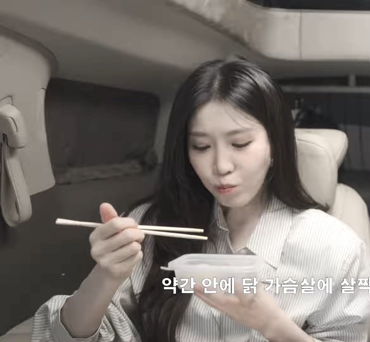 A woman in a striped shirt holds chopsticks over a container of food, with Korean text at the bottom reading '약간 안에 닭 가슴살에 살짝'.