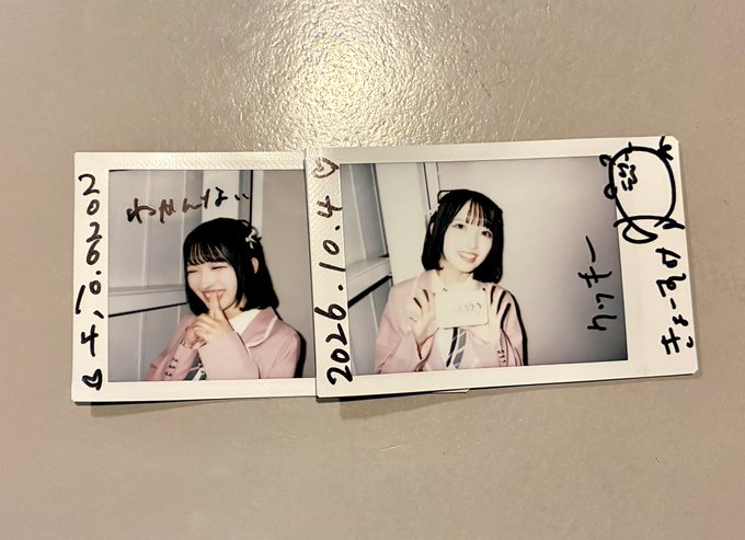 Two polaroid photos dated '2026.10.4' show a young woman in a pink jacket making peace signs and posing with a card, with a small cat doodle on the borders.