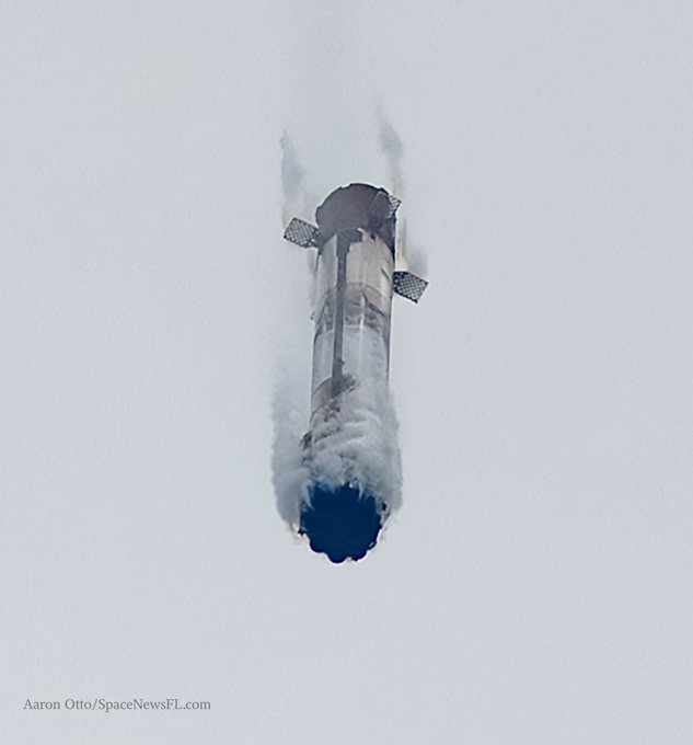 A SpaceX Starship rocket descends through the sky, trailing thick plumes of vapor from its grid fins and engine plume during a test flight. The image, credited to Aaron Otto/SpaceNewsFL.com, captures the dramatic atmospheric reentry of the massive spacecraft.