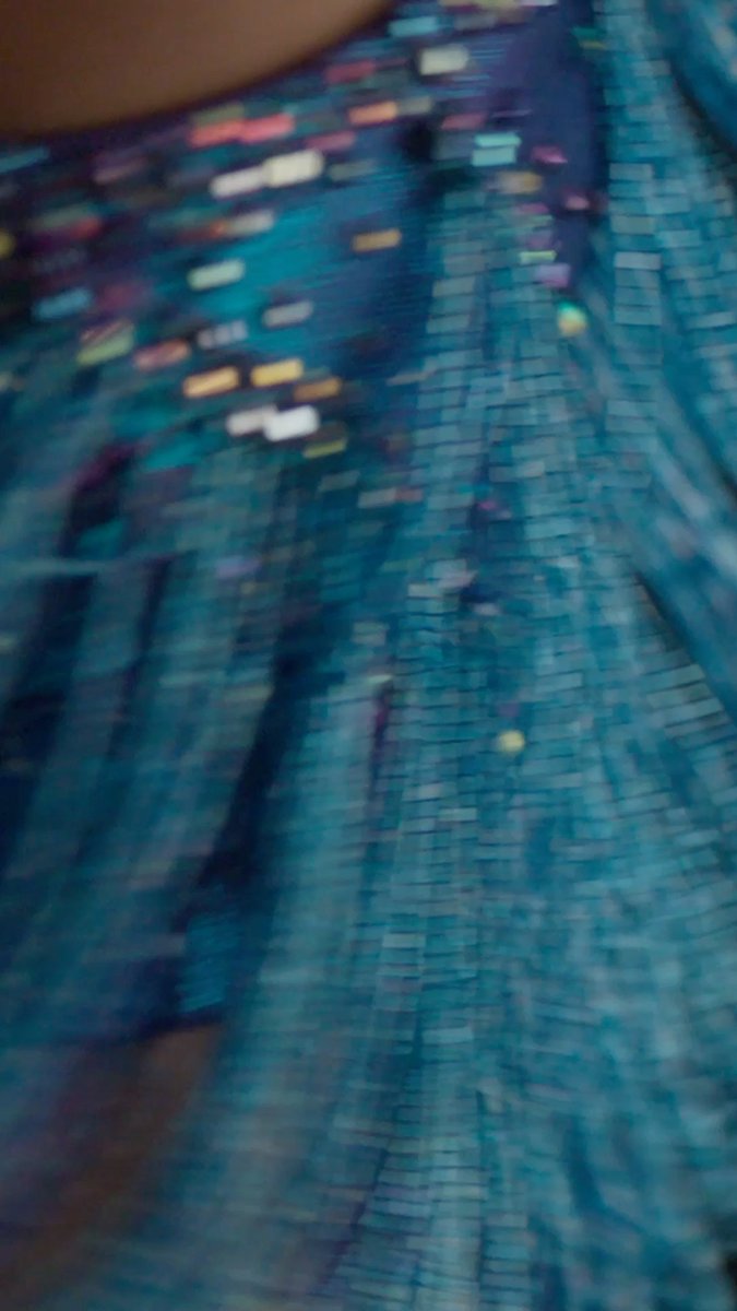 A blurry, close-up shot captures the shimmering blue sequins of a piece of clothing.
