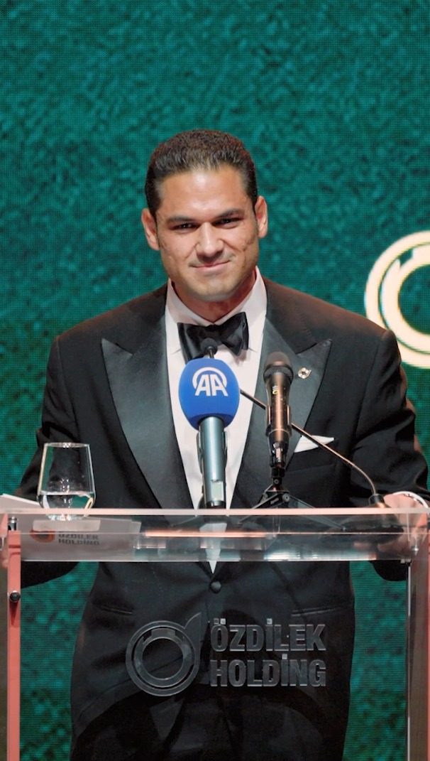 Emir Murat Özdilek, Chairman of the Board, stands at a podium branded with the "Özdilek Holding" logo, delivering a speech at the Özdilek Holding 55th Anniversary Gala as indicated by the Anadolu Agency (AA) microphone and the post's context.