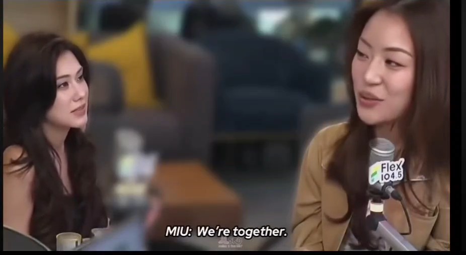 A scene from a film or show shows two women, with the one on the right speaking into a microphone labeled "Flex 104.5", and a subtitle reading "MIU: We're together."