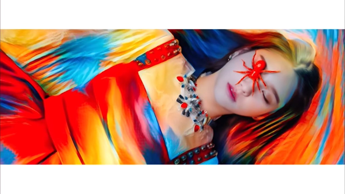 A stylized, colorful portrait of a woman with closed eyes, adorned with a red spider over her eye, wearing an ornate necklace and vibrant red and yellow attire.