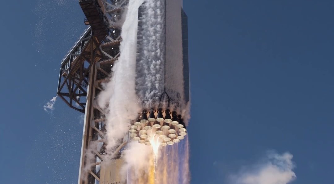 A SpaceX Starship rocket ignites its Raptor engines at liftoff, blasting off from the launch pad with massive plumes of white vapor and exhaust against a deep blue sky—capturing a moment of non-SI (i.e., "imperial") brute force as the vehicle begins its ascent.